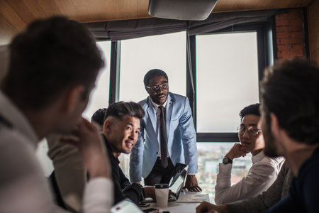 Multi ethnic people entrepreneurs meeting, small business concept. Afro american chief executive of big company presents new marketing strategy to coworkers gathering around a conference table.の写真素材