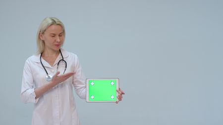 Portrait of a female doctor with white coat and tablet with green screenの写真素材