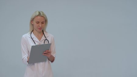 Portrait of a female doctor with white coat and stethoscope smiling looking into cameraの写真素材