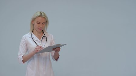 Female doctor with white coat and stethoscope smiling looking into camera on white backgroundの写真素材