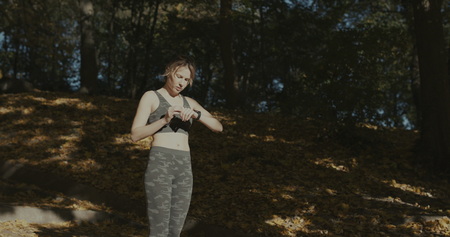 Beautiful young woman with mp3 player listening to tunes and running in city parkの写真素材