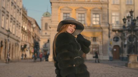 Young woman with beautiful blue eyes in a gray hat walking city street with headphonesの写真素材