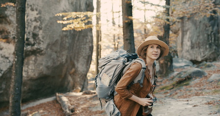 Active healthy Caucasian woman taking pictures with an vintage film camera on a forest rocksの写真素材