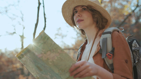 Close up Attractive young woman in stylish hat and a tourist map in her hands looking around