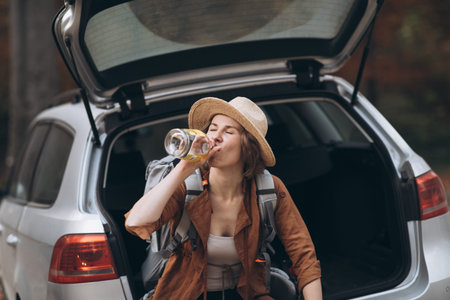 Portrait of a girl drinking alcohol from a bottle. Beautiful girl in a hat drinking a bottle of...