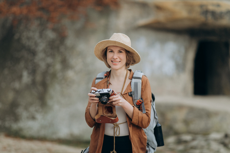 Active healthy Caucasian woman taking pictures with an vintage film camera on a forest rocksの写真素材