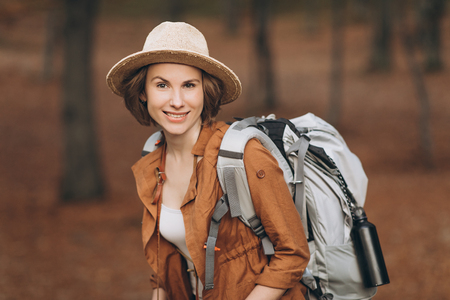 Portrait woman traveler with backpack looking at amazing forest, travel concept, space for text, atmospheric epic momentの写真素材
