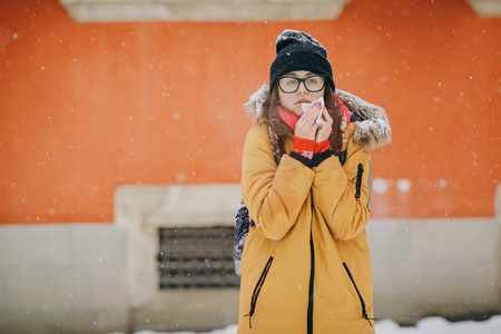Woman blowing her nose in winter. Sick brunette womanの写真素材