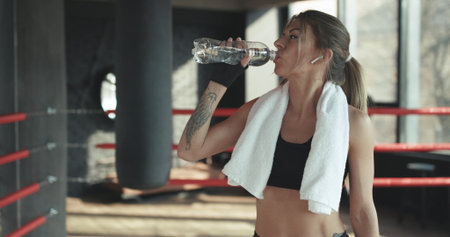 Closeup view of a young woman having a break after hard training by the boxing bag