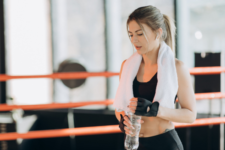 Closeup view of a Young Woman In Wireless Earphones having a break after hard training by the boxing bagの写真素材
