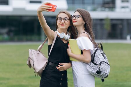 Two beautiful carefree girls taking selfie with a smart phone. Young joyful cheerful girls taking a selfie. Best friends taking photos. Tourism,destination and friendship conceptの写真素材