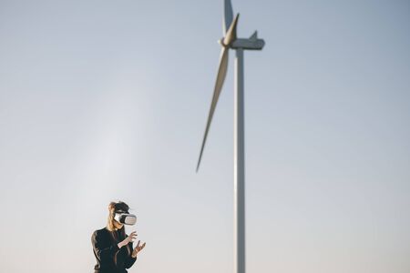 Engineer using virtual reality headset woman with vr headset. Engineer put on virtual reality headsets and looking around with wind turbine in the background.の写真素材