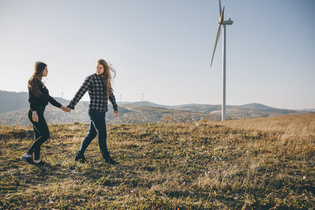 Young couple in love walking in the autumn park holding hands looking in the sunset.