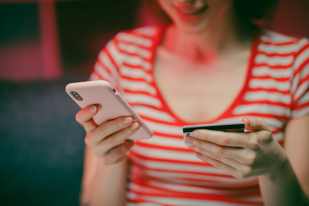 Young woman are buying online with a credit card while sitting on the sofa in the living room. Women...