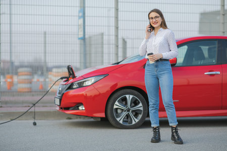 Electric car charging in street. Ecological Car Connected and Charging Batteries. Girl Use Coffee...