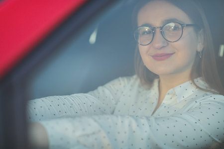 Portrait of a girl in glasses through the window of a car. Positive looking girl. Beautiful girl...