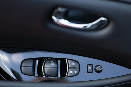 Detail on buttons controlling the windows in a car. Car interior details of door handle with windows...