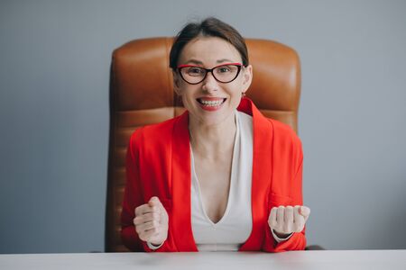 Cute girl holding her glasses and smiling. Beautiful happy businesswoman working at home officeの写真素材