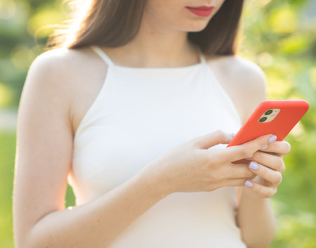 Girl Using Phone Screen Outdoors Hands holding smartphone. Woman Using Smartphone Relaxes on the...