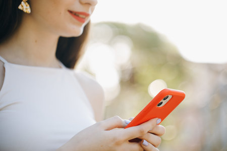 Mockup image of a woman using smart phone at outdoor and green nature background. Girl Hands holding...