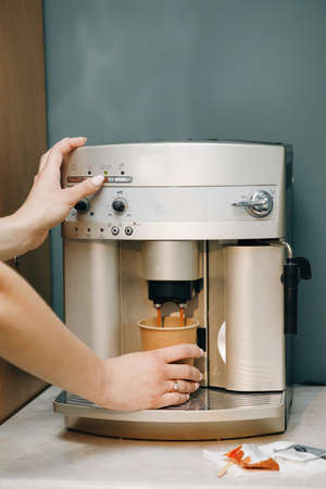 Close-up of a barista woman's hand making coffee by the coffee machine. Close-up view of woman's hands brewing a cup of coffeeの写真素材