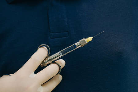 Close up of doctor holding syringe with dental anesthetic. Medicine, dentist, and health care concept. Dentist hand in glove holding syringe anesthesiaの写真素材
