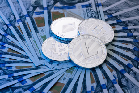 Dollar banknotes of various denominations on which lies the cryptocurrency. Silver Bitcoin Coin and...