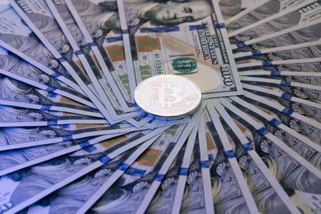 Diferent physical metal currency over 100 dollar bill of United States. Bitcoin crypto currency stacked with 100 dollar bills. New worldwide virtual internet money with USA banknotes.の写真素材