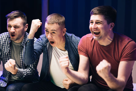 Loyal football fans supporting their team. Three men Watch a football or basketball game with...