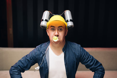 Man with beer helmet on the head sitting on the sofa and watching football. Expressing, screaming and emotionの写真素材