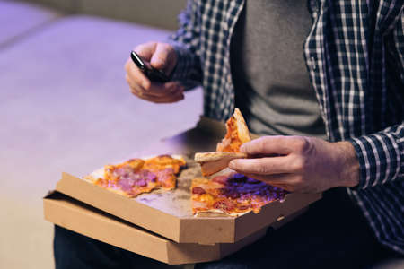 Unrecognizable hand opening carton box with delicious hot pizza. Hot tasty italian pizza from open box, food delivery service at party catering concept. Hand opens a pizza boxの写真素材