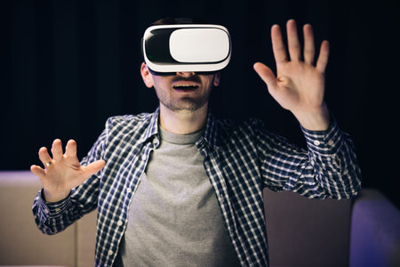 Man using modern 3D vr glasses indoors. Student playing using VR glasses. Handsome man wearing...