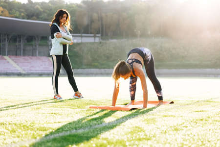 Young girl doing exercises under physiotherapist supervision. Patient Uses Physical Therapy to Recover from Surgery and Increase Mobility. The Doctor Works on Specific Muscle Groups or Jointsの写真素材