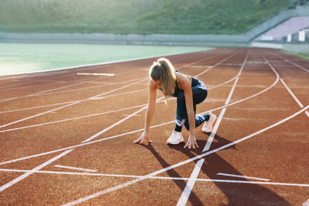 Runner taking off from the starting blocks on running track. Jogger activity. Female athlete....