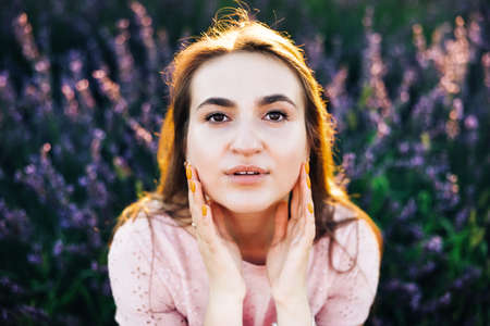 Portrait of beautiful romantic woman in fairy field of lavender. Woman on lavender field portrait. Young woman in dress outdoors. Girl in the lavender field at sunset.の写真素材