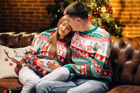 Happy couple enjoying Christmas together drinking hot tea. Couple Celebration New Year Near...