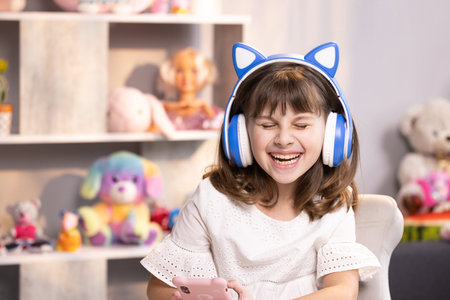 Cute small kid girl in headphones using funny editing application on smartphone, enjoying cool video...