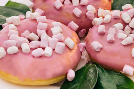Close-up of a delicious round donuts covered with sweet icing rotates on a bright background. Sweet dessert pink donutsの写真素材