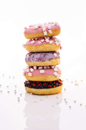 Shot of five sweet doughnuts stacked on top of each other in the form of a tower. Tasty delicious sweet donut with colorful sprinkles on white background.の写真素材
