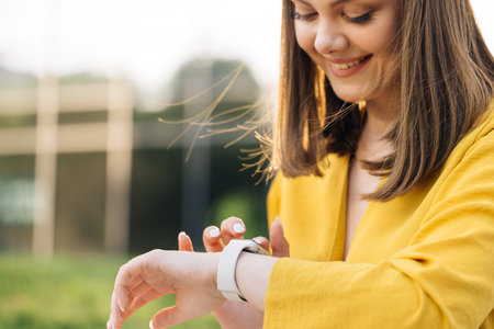 Smart watch. Smart watch on a womans hand outdoor. Appealing young elegant woman touching a smartwatch. Caucasian woman use her wearable smart watch and smilingの写真素材