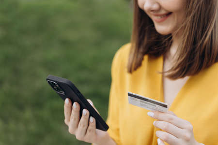 Online payment womans hands holding a credit card and using smart phone for online shoppingの写真素材