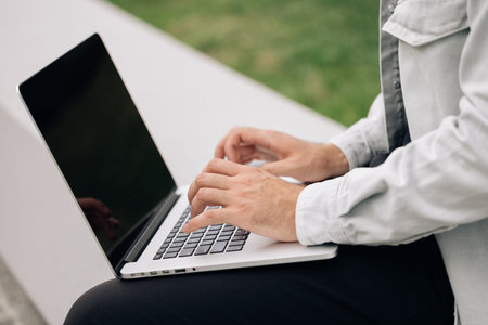 Male user hands typing on laptop keyboard sit on bench, mixed race ethnic businessman hipster...