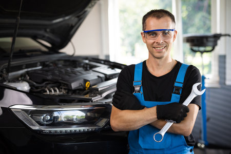 Portrait of european caucasian car mechanic in uniform with tools in his hands looks at the camera and laughs happily. Car service conceptの写真素材