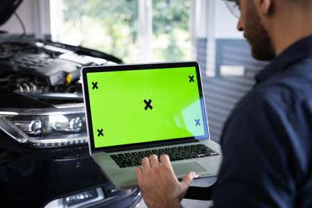 Car service mechanic uses laptop computer with green screen mock up chroma key car diagnostic software. Car Scanner Computer Diagnostics. Automotive Electronic Diagnosticの写真素材