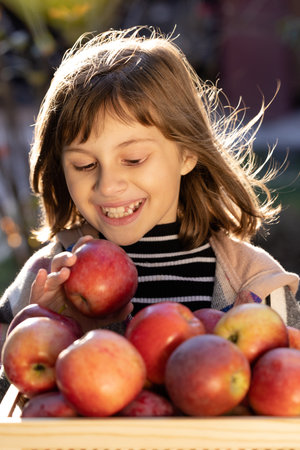 Attractive caucasian girl with apple. Smiling happy child with fresh fruit - emotional portrait close-up. Portrait of healthy girl eating big red apple.の写真素材
