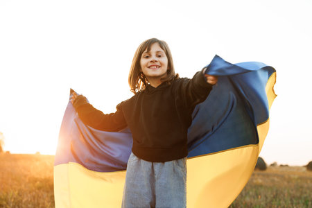 Portrait of Ukrainian child girl in embroidered shirt vyshyvanka with yellow and blue flag of Ukraine in field. Ukraines Independence Flag Day. Constitution day. Flag symbols of Ukraine. Kiev day.の写真素材
