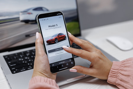 CALIFORNIA, USA - NOVEMBER 14, 2022: Smart phone shopping for a Tesla car browsing different models with the intent to purchase the vehicle online. Ordering Tesla model 3のeditorial素材