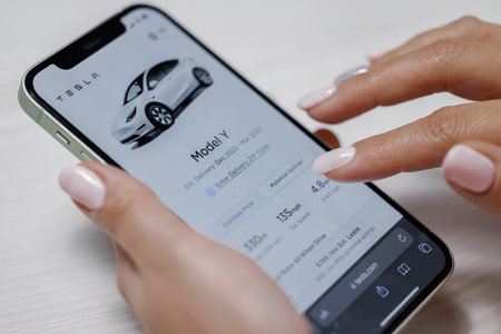 CALIFORNIA, USA - NOVEMBER 14, 2022: Ordering full self-driving autopilot for Tesla model Y. Smartphone shopping for a Tesla car browsing preferences with the intent to purchase the vehicle onlineのeditorial素材