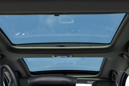 Panoramic glass sun roof in the modern car. Panoramic view inside car - double sunroof hatch with tinted glass. Sliding panoramic sunroof and luxurious leather seatsの写真素材