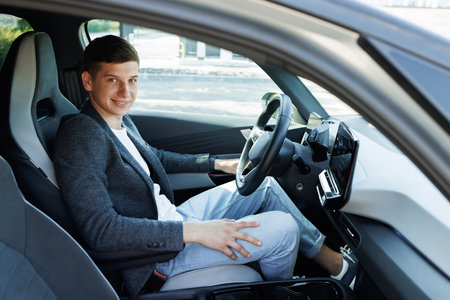 Attractive elegant happy man in good car. Confident businessman driving an expensive car and loking at camera.の写真素材